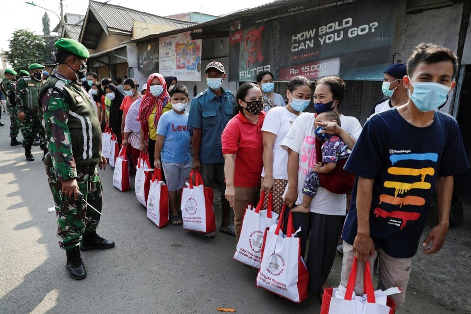 Locals wearing protective masks to prevent the spread of coronavirus disease (COVID-19) stand in line as they receive assistance given by Indonesian President in Jakarta, Indonesia