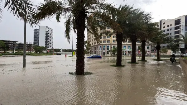 Flooded urban scene in the UAE with palm-lined streets and submerged buildings during Summer 2022, illustrating the impact of flash floods in arid climates.